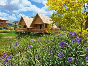 a log cabin with purple flowers in front of it at คูณ-เนื่อง ฟาร์ม สเตย์ หัวหิน Koon & Nueang Farm Stay Hua Hin in Ban Bo Fai