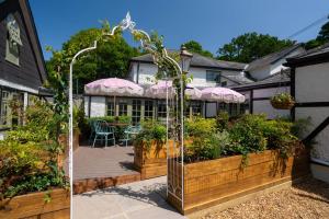 a house with a patio with plants and a garden at High Corner Inn in Ringwood