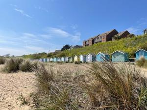 una fila de cabañas de playa en una playa de arena en Beach retreat! en Pakefield