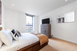 a white bedroom with a large bed and a television at Immaculate 3BR apt in Hackney in London