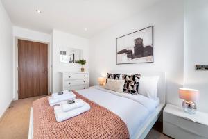 a white bedroom with a large bed with two towels at Immaculate 3BR apt in Hackney in London