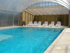 a large swimming pool with white chairs in a building at Camping Moulin de Collonge in Saint-Boil