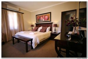 - une chambre avec un lit, un bureau et une télévision dans l'établissement Celtis Country Lodge & Restaurant, à Middelburg