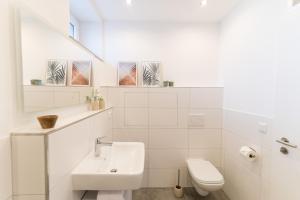 een witte badkamer met een wastafel en een toilet bij DWELLSTAY - Apartment mit eigenem Eingang I 30qm I zentrale Lage I Bad I Küche I Terrasse I TV in Fulda