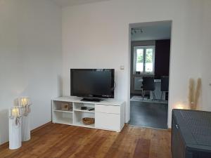una sala de estar con TV en un centro de entretenimiento blanco en Ferienwohnung NatuRaum en Gräfenberg