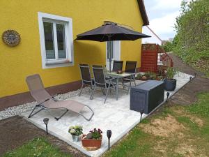 een patio met een tafel en stoelen en een parasol bij Ferienwohnung NatuRaum in Gräfenberg