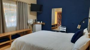 a blue bedroom with a white bed and a window at Steps Accommodation in Gobabis