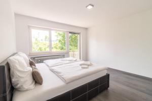 a bedroom with a large white bed with a window at Unique: Geräumige 4 Zimmerwohnung in Tuttlingen mit Sauna, Fitness und Netflix OG in Tuttlingen
