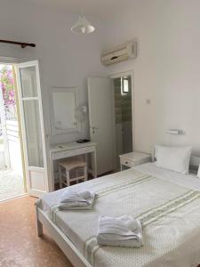 a white bedroom with a bed and a mirror at Korali Hotel in Antiparos Town