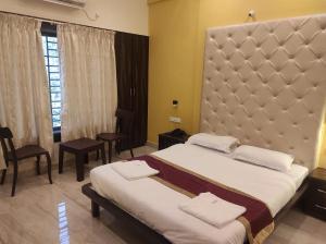1 dormitorio con 1 cama grande y cabecero grande en Hotel Deepak Executive, Ganpatipule en Ganpatipule