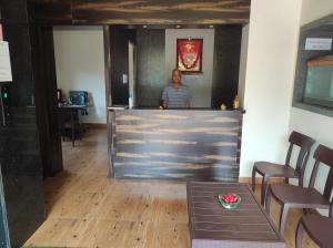 a man standing behind a bar in a restaurant at Hotel Deepak Executive, Ganpatipule in Ganpatipule