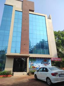 a white car parked in front of a building at Hotel Deepak Executive, Ganpatipule in Ganpatipule