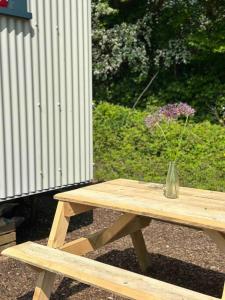 a vase of flowers sitting on a wooden picnic table at Cleo’s Hut in Cowfold