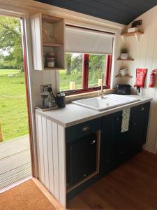 a small kitchen with a sink and a window at Cleo’s Hut in Cowfold