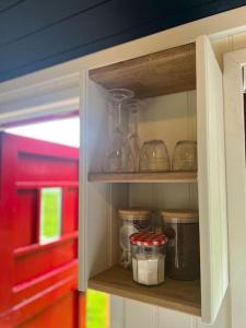 a cabinet filled with glass jars and other items at Cleo’s Hut in Cowfold