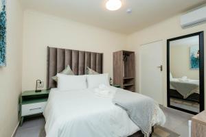 una camera da letto con un grande letto bianco e uno specchio di Greenshade Lodge a Johannesburg