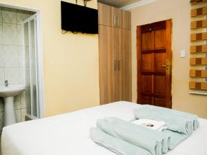 Princeville Guest Lodge في سويتو: غرفة نوم عليها سرير وفوط