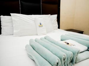 Princeville Guest Lodge في سويتو: سرير عليه وسائد زرقاء وبيضاء