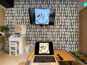a laptop on a table with a tv on a wall at TOKYO-W-INN Asakusa in Tokyo