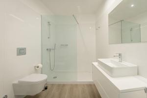 a white bathroom with a shower and a sink at Oceanside East in Ponta Delgada