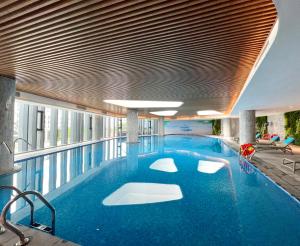 a large swimming pool with blue water in a building at HB Serviced Apartment - Alacarte Hạ Long in Ha Long