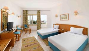 ein Hotelzimmer mit 2 Betten und einem TV in der Unterkunft Menaville Resort in Hurghada