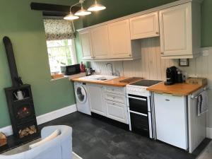 a kitchen with white cabinets and a stove at The Cornish Peak by StayStaycations in Camelford