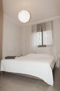 a white bedroom with a white bed and a window at Стильные апартаменты Dotan in Netanya