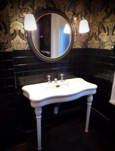 een badkamer met een witte wastafel en een spiegel bij Le 1930 in Hénin-Beaumont