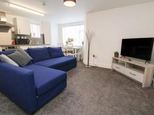 sala de estar con sofá azul y TV en Apartment 1, en Conwy