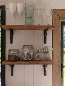 a wooden shelf with glasses and bowls on it at Kenny’s Hut in Cowfold