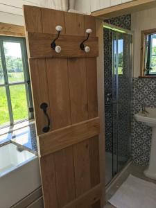 a wooden door in a bathroom with a shower at Kenny’s Hut in Cowfold