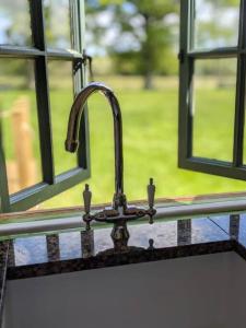 a kitchen sink with a faucet in front of a window at Kenny’s Hut in Cowfold