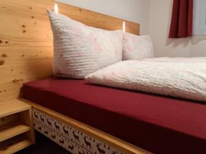 1 cama con cabecero de madera y colchón rojo en Apartment Grafenauer, en Sankt Gallenkirch