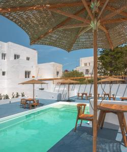 a pool with tables and chairs and an umbrella at VOCA HOTEL & SUITES in Kamari