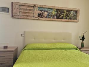 a bedroom with a green bed and a painting on the wall at B&B Monteleo Salento in Morciano di Leuca