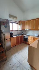 a kitchen with wooden cabinets and a stainless steel refrigerator at BAREFOOT COTTAGE in Skiathos Town