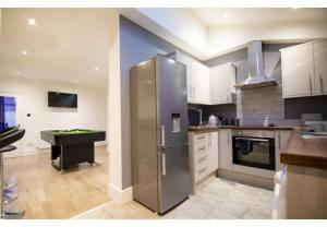 uma cozinha com um frigorífico de aço inoxidável e uma mesa de bilhar em Stunning Bolton abode – Pool table – Parking em Bolton