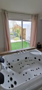 a bath tub in a room with a window at L'Essentiel - Love 85 in Talmont
