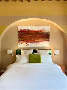 ein Schlafzimmer mit einem weißen Bett mit einem Gemälde darüber in der Unterkunft Green Escape Guesthouse with Pool in Villa in Florenz