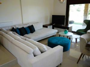 a living room with a white couch and a blue stool at Blue Dream Villa in Nea Skioni