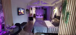 Cette chambre violette comprend un lit et un canapé. dans l'établissement L'Essentiel - Love 85, à Talmont-Saint-Hilaire