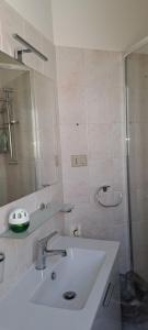 Un baño blanco con lavabo y ducha. en Piero's Apartment Calasetta, en Calasetta