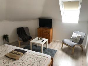 1 dormitorio con 1 cama, TV y silla en Szabó Vendégház Zamárdi, en Zamárdi