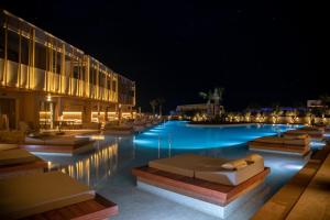 a swimming pool at night with chaise lounges at SENSEANA Sea Side Resort & Aquadventure in Hersonissos