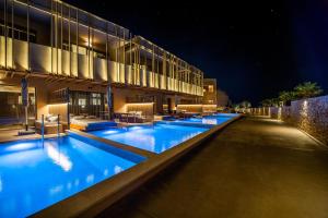 a row of swimming pools in front of a building at night at SENSEANA Sea Side Resort & Aquadventure in Hersonissos