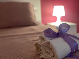 a rolled up towel with a blue ribbon on a bed at A casa di Miele in Campagnano di Roma