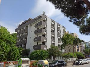 un edificio de apartamentos alto con coches estacionados frente a él en Dias Hotel, en Kusadasi