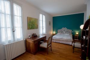 um quarto com uma cama, uma secretária e janelas em d’un jardin à l’autre em Tarbes