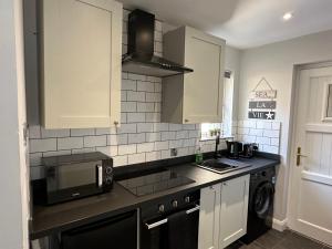 a kitchen with white cabinets and a black microwave at 2 hunters lane Donaghadee in Donaghadee